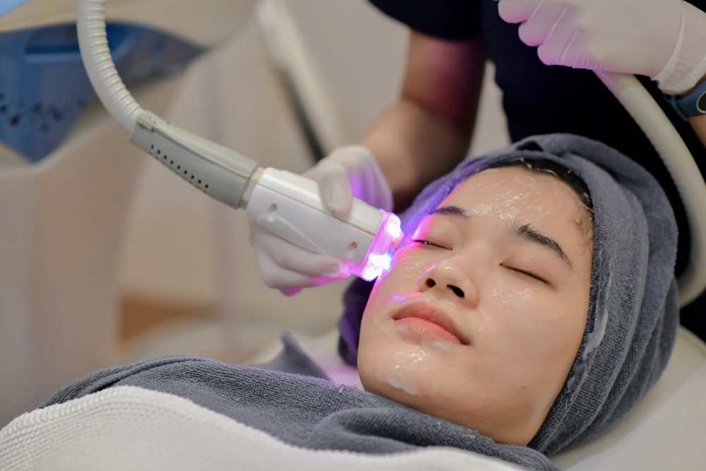 Closeup Of Beautician Using Laser Therapy For Facial Skin Rejuvenation. Beautiful Healthy Woman Face Getting Skin Resurfacing In Spa Salon.